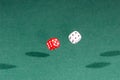 Two red and white dices falling on a green table Royalty Free Stock Photo