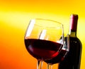 Two red wine glasses near the bottle against golden lights background Royalty Free Stock Photo