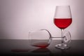 Two red wine glasses on a white background, one glass half full the second lies, spilled wine Royalty Free Stock Photo