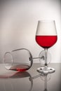 Two red wine glasses on a white background, one glass half full the second lies, spilled wine Royalty Free Stock Photo