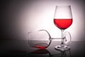 Two red wine glasses on a white background, one glass half full the second lies, spilled wine Royalty Free Stock Photo