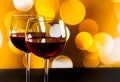 Two red wine glasses on wood table against golden bokeh lights background Royalty Free Stock Photo