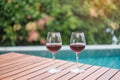 Two Red wines glasses near swimming pool. Summer travel, vacation, holiday and happy weekend concept