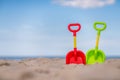 Green and red plastic shovels on the beach Royalty Free Stock Photo