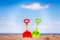 Green and red plastic shovels on the beach Royalty Free Stock Photo