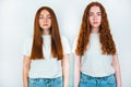 Two redheaded young women both look serious standing on isolated white backgroung