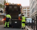 Two refuse collection workers loading garbage into waste truck emptying containers