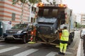 Two refuse collection workers loading garbage into waste truck emptying containers