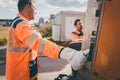 Two refuse collection workers loading garbage into waste truck Royalty Free Stock Photo