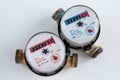 A two residential water meters on white background. A used up mechanical water meter close-up.