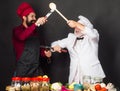 Two restaurant chefs or bakers in uniform fighting in kitchen. Cooking food. Competition of chef. Royalty Free Stock Photo