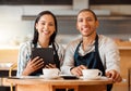 Two restaurant workers planning on a digital tablet in a small business. Young mixed race colleagues having coffee while Royalty Free Stock Photo