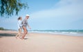 Two retired Asian couples happily run hand in hand on the beach Royalty Free Stock Photo