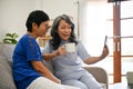 Two retired middle-aged Asian women enjoying talking with their grandchild through a video call Royalty Free Stock Photo