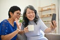 Two retired middle-aged Asian women are talking with their grandchild through a video call Royalty Free Stock Photo