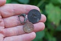Two retro coins and a piece of an old metal buckle lie on the fingers
