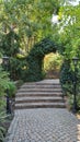 Two retro streetlight lanterns by sides of paved path with steps in park with green hedge arch Royalty Free Stock Photo