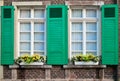 Two retro windows with green wooden shades with yellow flowers on red brick building Royalty Free Stock Photo