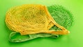 Two reusable cotton net bags or mesh bags on coloured background