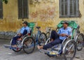 Two rickshaw drivers wait for customers.