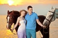 Two riders on horseback at sunset on the beach. Lovers ride horseback. Young beautiful man and woman with a horses at the sea. Royalty Free Stock Photo