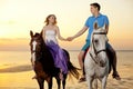 Two riders on horseback at sunset on the beach. Lovers ride horseback. Young beautiful man and woman with a horses at the sea. Royalty Free Stock Photo