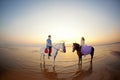 Two riders on horseback at sunset on the beach. Lovers ride horseback. Young beautiful man and woman with a horses at the sea. Royalty Free Stock Photo