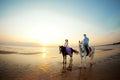 Two riders on horseback at sunset on the beach. Lovers ride horseback. Young beautiful man and woman with a horses at the sea. Royalty Free Stock Photo