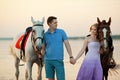 Two riders on horseback at sunset on the beach. Lovers ride horseback. Young beautiful man and woman with a horse at the sea. Rom Royalty Free Stock Photo