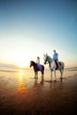 Two riders on horseback at sunset on the beach. Lovers ride horseback. Young beautiful man and woman with a horse at the sea. Rom Royalty Free Stock Photo