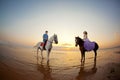 Two riders on horseback at sunset on the beach. Lovers ride horseback. Young beautiful man and woman with a horse at the sea. Rom Royalty Free Stock Photo