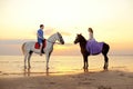 Two riders on horseback at sunset on the beach. Lovers ride horseback. Young beautiful man and woman with a horse at the sea. Rom Royalty Free Stock Photo