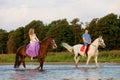 Two riders on horseback at sunset on the beach. Lovers ride horseback. Young beautiful man and woman with a horses at the sea. Royalty Free Stock Photo