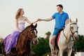 Two riders on horseback at sunset on the beach. Lovers ride horseback. Young beautiful man and woman with a horses at the sea.