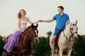 Two riders on horseback at sunset on the beach. Lovers ride horseback. Young beautiful man and woman with a horse at the sea. Rom Royalty Free Stock Photo