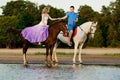 Two riders on horseback at sunset on the beach. Lovers ride horseback. Young beautiful man and woman with a horse at the sea. Rom Royalty Free Stock Photo