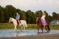 Two riders on horseback at sunset on the beach. Lovers ride horseback. Young beautiful man and woman with a horse at the sea. Rom Royalty Free Stock Photo