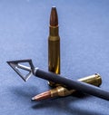 Two 30.06 rifle bullets with a three blade broadhead attached to an arrow shaft