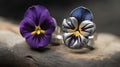 two rings with flowers on them sitting on a piece of wood next to a flower that is purple, yellow, and white in color Royalty Free Stock Photo