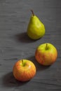 Two ripe apples and one pear on a dark gray background Royalty Free Stock Photo