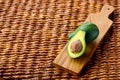 Two ripe avocados on wooden background: one whole and one cut. Royalty Free Stock Photo