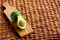 Two ripe avocados on wooden background: one whole and one cut. Royalty Free Stock Photo