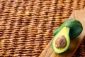 Two ripe avocados on wooden background: one whole and one cut. Royalty Free Stock Photo