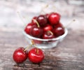 Two ripe berries on a background of a glass bowl full of cherries on a wooden background