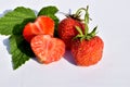Two ripe strawberries and one cut in half on white Royalty Free Stock Photo