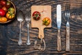 Two ripe tomatoes on cutting board.Fork and knife on dark wooden table. view from above Royalty Free Stock Photo