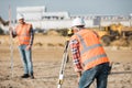 Road construction workers using measuring device on the field