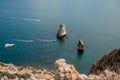 Two rocks stick out of the water in the middle of the turquoise sea. Scenic ocean view. Speed boat sails on the sea