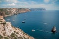 Two rocks stick out of the water in the middle of the turquoise sea. Scenic ocean view. Speed boat sails on the sea