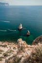 Two rocks stick out of the water in the middle of the turquoise sea. Scenic ocean view. Speed boat sails on the sea